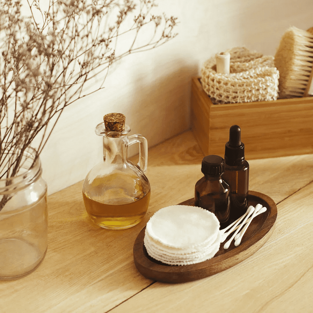 Spa essentials: dried flowers, essential oils, cotton pads, and wooden basket with bath items.